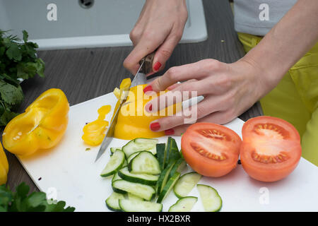 Frauenhand Tomate hinter frisches Gemüse schneiden. Stockfoto