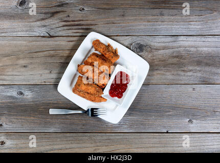 Draufsicht auf eine Portion gebratener Fisch plus Ketchup auf rustikalen Holztisch Stockfoto