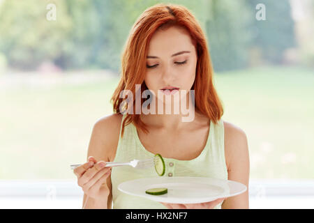 Frau, die eine Gurkenscheibe isst Stockfoto