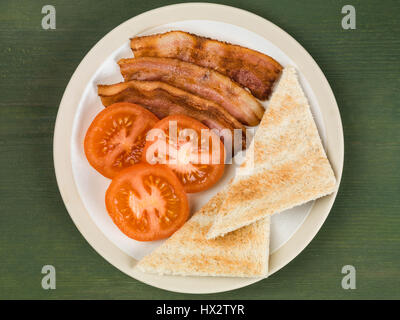 Authentische Flach bunte Englisches Frühstück, gebratenen Speck, Ei, Sunny Side Up, gegrillte Tomaten mit Toast vor einem grünen Hintergrund Stockfoto