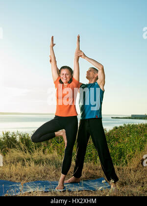 Lächelndes Paar machen Yoga Übungen im Freien Stockfoto