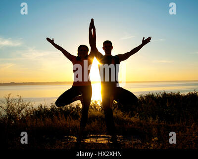 Lächelndes Paar machen Yoga Übungen im Freien Stockfoto