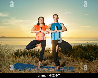 Lächelndes Paar machen Yoga Übungen im Freien Stockfoto