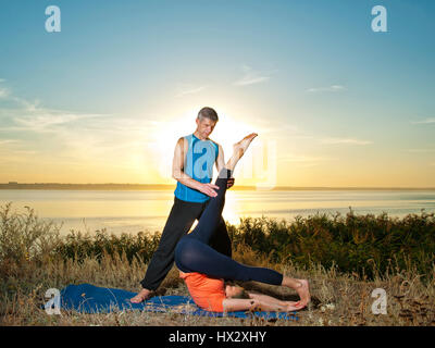 Lächelndes Paar machen Yoga Übungen im Freien Stockfoto