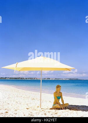 Frau sitzend unter Dach, Grace Bay Beach, Turks- und Caicosinseln Stockfoto