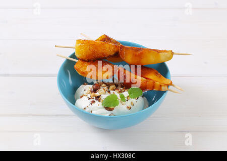 Schüssel mit Birne und Orange-Spieße mit Joghurt, gehackten Nüssen und Mandeln Stockfoto