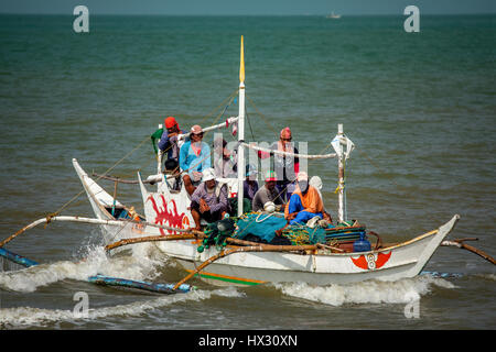 Überladene Filipino Fischerboot voller Männer und Teen Boys macht eine Landung am Strand von BayBay in Roxas City, Insel Panay, Philippinen. Stockfoto