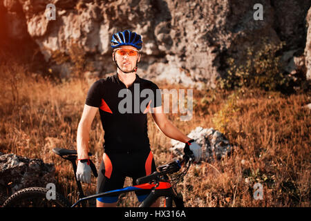 Porträt eines Radfahrers in Helm und Sonnenbrille auf dem Mountainbike. Aktiv Sport in der Natur. Stockfoto