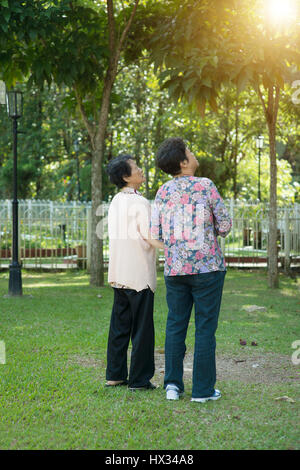 Offenen Schuß von hinten sehen asiatische ältere Frauen Hand in Hand und Fuß in Outdoor-Park am Morgen. Stockfoto