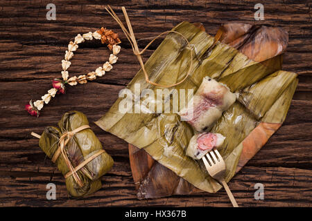 Khao Tom Matte - Thai Dessert - klebrigen Reis, Bananen und schwarzen Bohnen eingewickelt in Bananenblatt - Still-Leben hautnah auf hölzernen Hintergrund Stockfoto