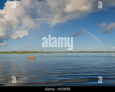 Iquitos, Peru - 16. Mai 2016: Regenbogen über Amazonas und Kajak mit den Kanuten. Stockfoto