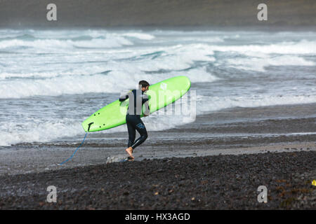 Mann mit grünen Surfbrett am Famara Strand Lanzarote Stockfoto