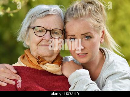 Großmutter und Enkelin. Junge Frau kümmert sich sorgfältig von einer älteren Frau. Stockfoto