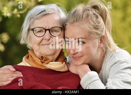 Großmutter und Enkelin. Junge Frau kümmert sich sorgfältig von einer älteren Frau. Stockfoto