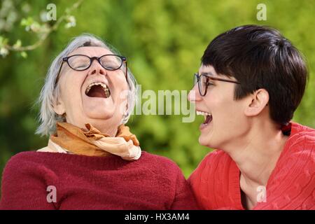 Großmutter und Enkelin. Junge Frau kümmert sich sorgfältig von einer älteren Frau. Stockfoto