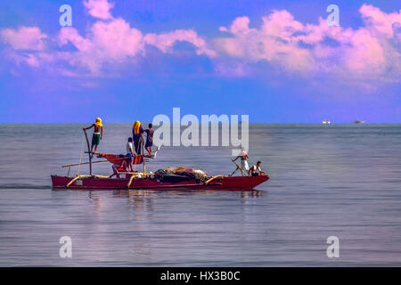 Die philippinische Crew ein Ausleger Angeln Boot Köpfe zurück zum Ufer nach einem langen Tag der Arbeit ihre Seine Netze in den Golf von Panay. Haus ist BayBay Beac Stockfoto