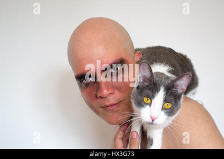 Mann mit Make-up auf seine Augen und einer Katze auf der Schulter Stockfoto