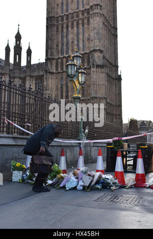 London, UK. 23. März 2017. Ein Mann legt Blumen außerhalb des Parlamentsgebäudes am Tag nach dem Terroranschlag von Westminster in London. Mitglieder der Öffentlichkeit und Polizei legten Notizen und Blumen zum Gedenken an die Opfer des Angriffs. Bildnachweis: Jacob Sacks-Jones/Alamy Live-Nachrichten. Stockfoto