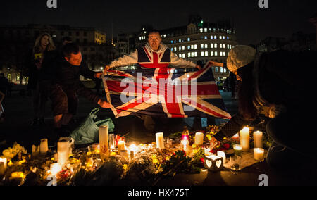 Ein Mann namens John Loughrey Union Jack mit einem Zitat drauf vor Kerzen auf eine Kerze hält beleuchtet Mahnwache gehalten zu Ehren der Opfer des Westminster-Terror-Anschlag. Stockfoto