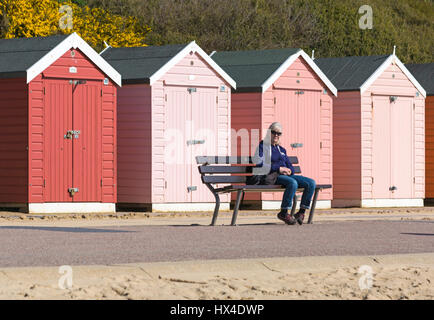 Bournemouth, Dorset, UK. 25. März 2017. UK-Wetter: schönen warmen, sonnigen Tag als Besucher gehen ans Meer machen das Beste aus der Sonne an den Stränden von Bournemouth. Frau sitzt auf der Bank vor Strandhütten, genießen die Sonne am Strand von Bournemouth. Bildnachweis: Carolyn Jenkins/Alamy Live-Nachrichten Stockfoto