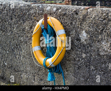 Eine leuchtende lebensrettende Ring und Auftrieb hängt an der Hafenmauer in Ballintoy auf der nördlichen Küste von Irland Stockfoto