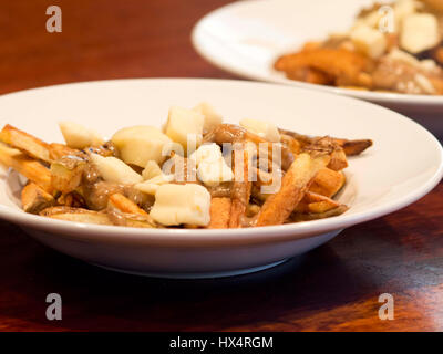 Eine Schüssel mit hausgemachten Poutine, einem kanadischen Gericht mit Pommes frites, braunen Soße und Käse Quark. Stockfoto
