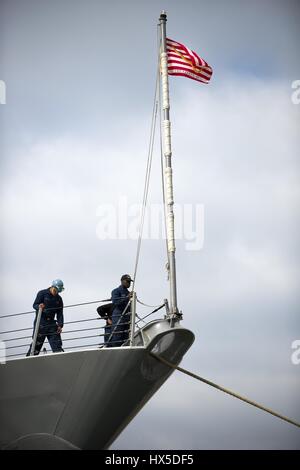 Ein Matrose senkt die Navy jack an Bord der Arleigh-Burke-Klasse geführte Flugkörper Zerstörer USS Preble wie es bereitet sich auf die Naval Base San Diego für eine geplante Abfahrt im Gange, San Diego, Kalifornien, 6. Februar 2013. Stockfoto