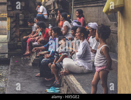 Ein kleines Mädchen schaut zu, wie ihre Familie am Tirta Empul Tempel in Bali, Indonesien zu beten Stockfoto