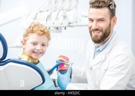 Der junge zeigt, wie man auf künstliche Kiefer in der Zahnarztpraxis Zähne putzen Zahnarzt Stockfoto
