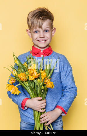 Kleines schönes Kind mit einem Strauß Tulpen. Sohn macht Mutter Blumen zum Frauentag, Muttertag. Geburtstag. Zum Valentinstag. Frühling. Stockfoto