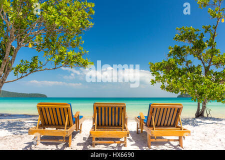 Drei Liegestühle auf einem weißen Sandstrand mit Blick auf einen ruhigen leer tropischen Meer. Niedrigen Winkel. Stockfoto