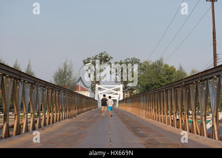 die Rückseiten von zwei Kindern, die zu Fuß entfernt, über eine Kreuzung aus Metall Flussbrücke in Kambodscha. Stockfoto