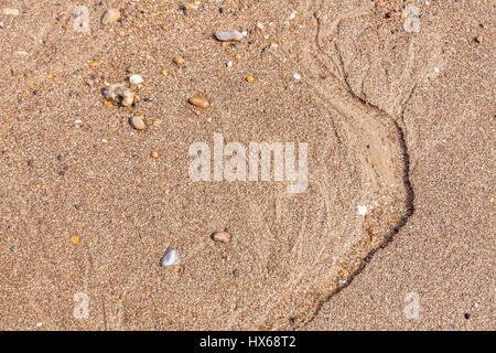 Kiesigen Sand Textur. Nahaufnahme von oben auf einen Sandstrand mit kleinen Steinen und Marken durch die Strömung von Wasser, England, Großbritannien Stockfoto