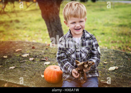 Schön lässig blonden Kind sitzt im Freien auf Tisch und lachen. Herbst. Outdoor portrait Stockfoto