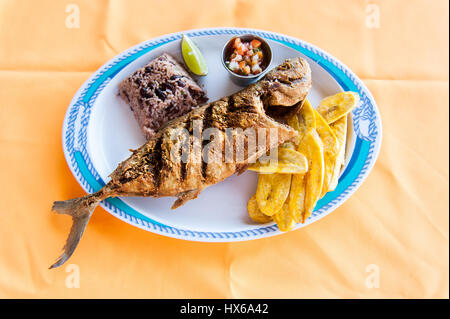 Ganze Fische, Reis mit Bohnen und Kochbananen Chips Stockfoto