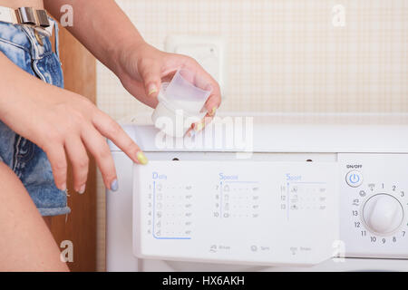 Nahaufnahme eines Mädchens Hand Waschmaschine einstellen. Stockfoto