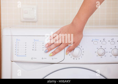 Nahaufnahme eines Mädchens Hand Waschmaschine einstellen. Stockfoto