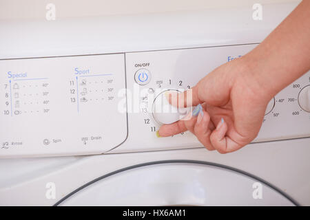 Nahaufnahme eines Mädchens Hand Waschmaschine einstellen. Stockfoto