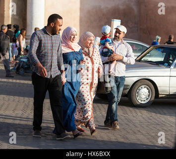 Meknès, Marokko.  Zwei Paare, überqueren die Straße an der Bab Mansour.  Frauen in zeitgenössische konservative Kleidung, Männer in westlicher Kleidung. Stockfoto