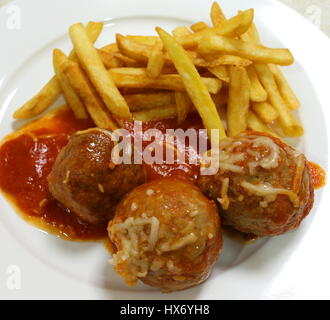 Hausgemachte Hackfleischbällchen in Sauce serviert mit Pommes frites Stockfoto