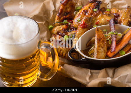 Würzige Hähnchenflügel mit Hot Chili Jam, gebackene Kartoffeln und Lila Karotten Stockfoto