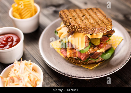 Große hausgemachte Sandwich mit Roastbeef, Speck, Gurken, Baby-Spinat und Krautsalat Dressing in geröstetem Brot Stockfoto