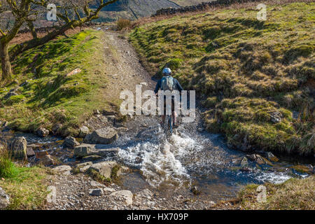 Mountainbiker, die Kreuzung schwarz Beck in Kentmere Cumbria Stockfoto