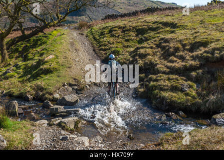 Mountainbiker, die Kreuzung schwarz Beck in Kentmere Cumbria Stockfoto