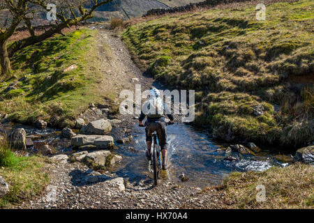 Mountainbiker, die Kreuzung schwarz Beck in Kentmere Cumbria Stockfoto