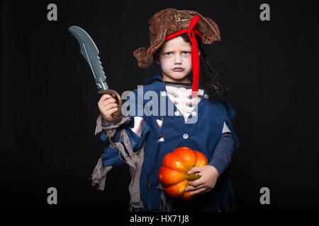 Entzückender junge gekleidet in ein Piraten-Outfit, Süßes oder Saures spielen für Halloween. Studio-Porträt über schwarzen Hintergrund Stockfoto