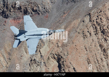 Vereinigte Staaten Marine F/A-18E Super Hornet auf niedrigem Niveau durch eine Wüste Schlucht fliegen. Stockfoto