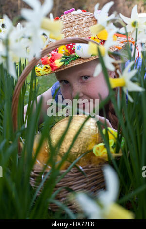 Mädchen mit Ostern Motorhaube auf ein Easter Egg hunt in Lancashire, UK Stockfoto