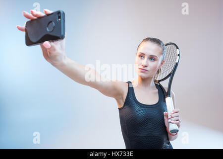 junge Frau mit Tennisschläger machen Selfie auf smartphone Stockfoto