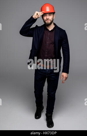 Mann in einem schwarzen Anzug und Bau Helm Blick zur Seite und halten schwarze Ordner auf grauem Hintergrund Stockfoto